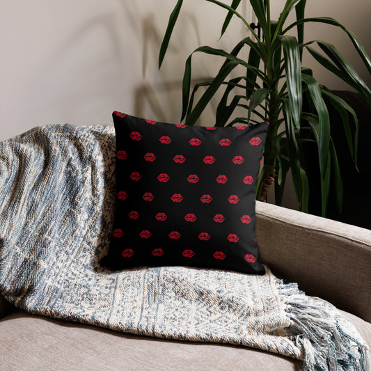 Black pillow with red pattern on a couch next to a plant